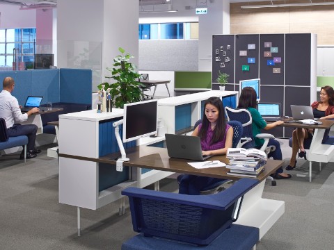 People working at computers in a Hive Setting furnished with Public Office Landscape in blue and white, and with blue Mirra 2 Chairs.