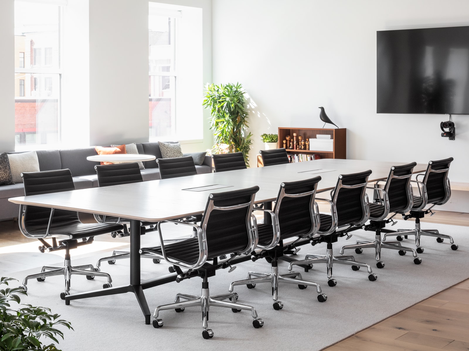 A large, well-lit conference room with a Headway Table and ten black Eames Aluminium Group Chairs.