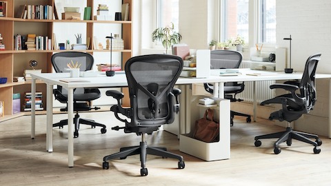 An open-plan office with four desks arranged together two-by-two, each with an Aeron Chair pulled in.